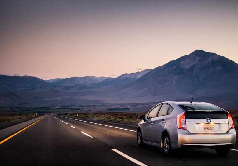 A car on an open road heading towards the hills